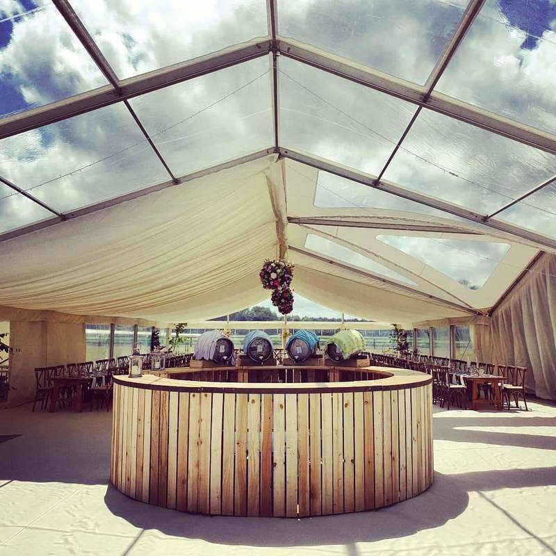 large rustic reclaimed wood bar unit. Positioned within a clear roof marquee, ready for a wedding